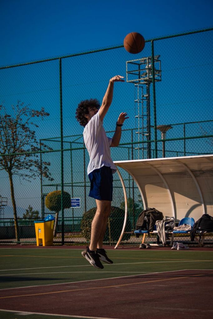 Young male basketball player mid-air shooting on an outdoor court in Sakarya, Turkey.