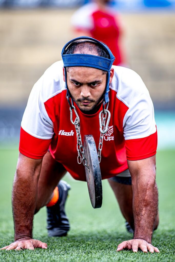 Athlete intensely training with weighted head harness outdoors.