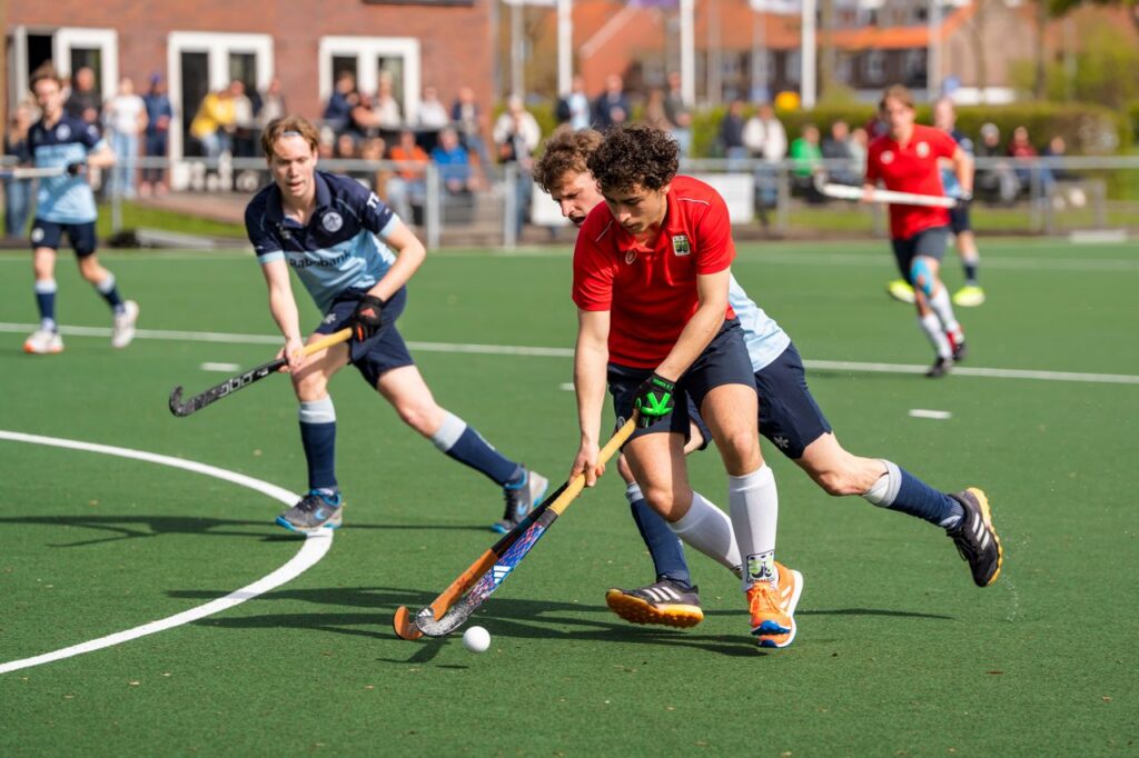 Athletes compete in a dynamic field hockey match under the bright sun, showcasing teamwork and skill.